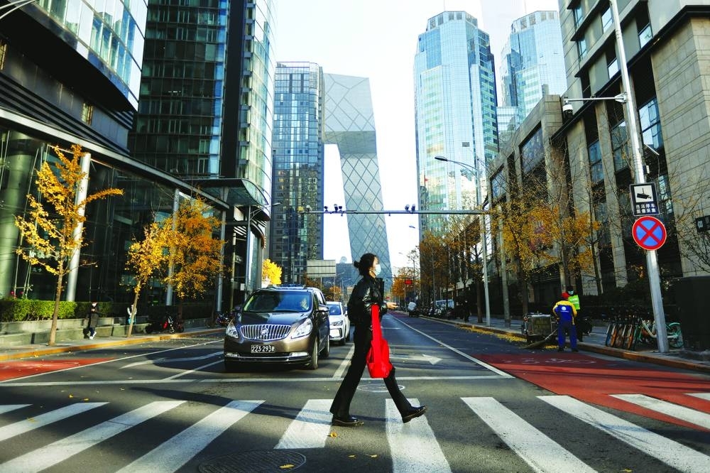 A woman walks across the street during morning rush hour, following the outbreak of the coronavirus disease, in the Central Business District in Chaoyang District, Beijing, China, yesterday.