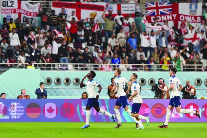 England’s forward Bukayo Saka (left) celebrates with teammates after scoring England’s fourth goal during the FIFA World Cup Group B match at the Khalifa International Stadium yesterday. (AFP)