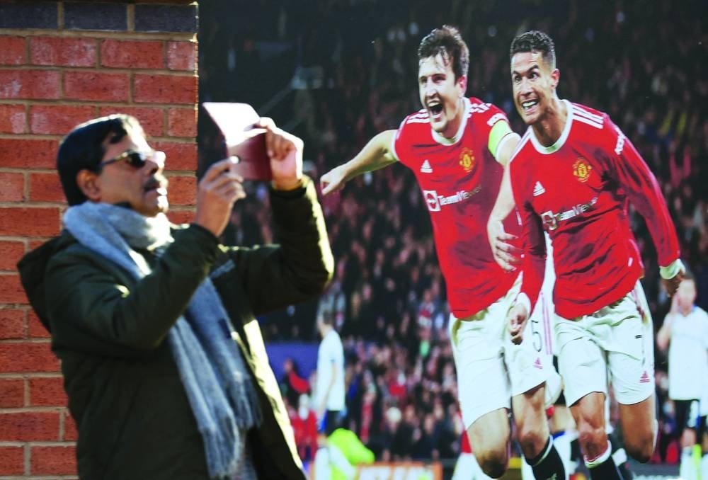 A man takes a photo outside Old Trafford next to a Cristiano Ronaldo picture after it was announced by the club that Ronaldo would be leaving Manchester United.