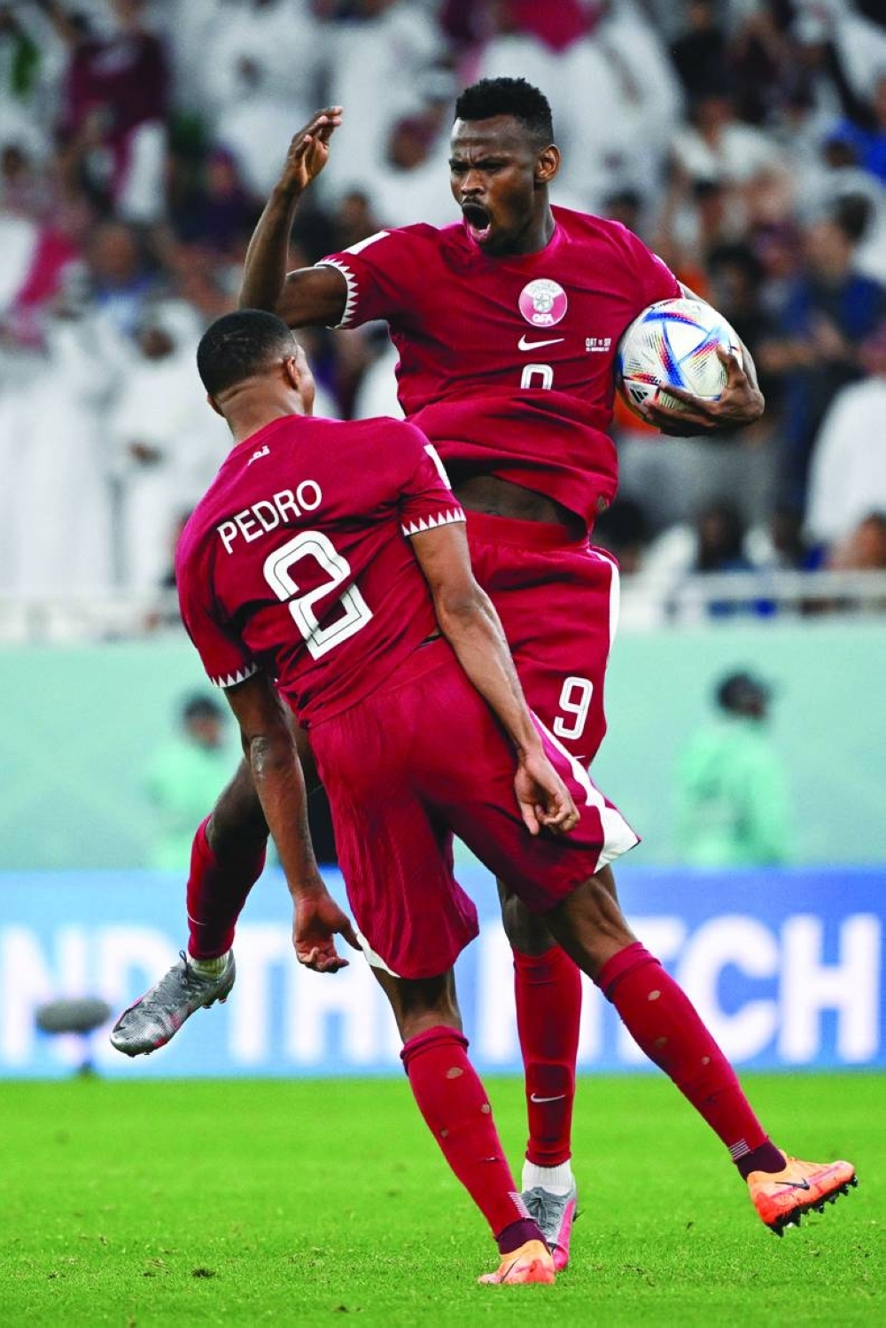 Qatar's forward #09 Mohammed Muntari celebrates scoring his team's first goal with his teammate Qatar's defender #02 Pedro Miguel during the Qatar 2022 World Cup Group A football match between Qatar and Senegal at the Al-Thumama Stadium in Doha on November 25, 2022. (Photo by OZAN KOSE / AFP)