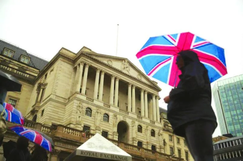 A pedestrian shelters under a Union Flag umbrella in front of the Bank of England in London. (Reuters)