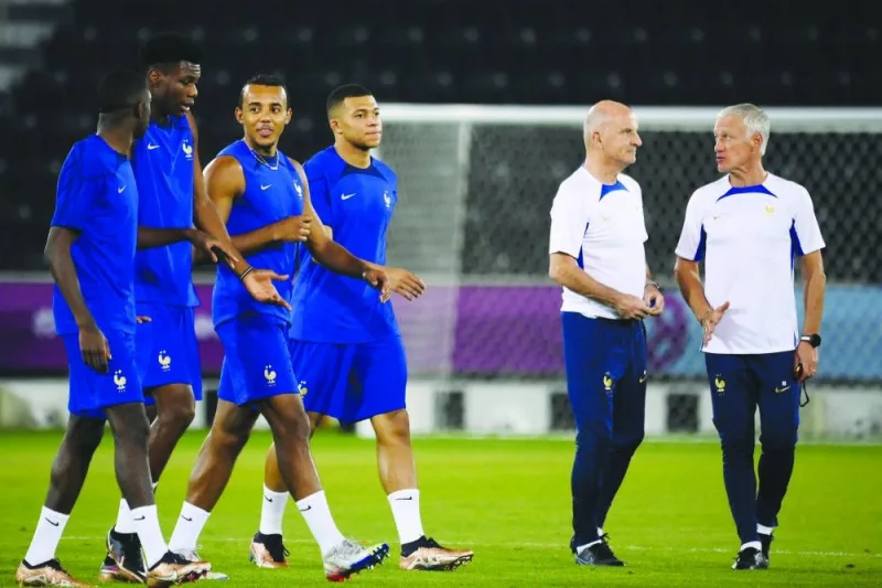 France's coach Didier Deschamps (right) and France's assistant coach Guy Stephan (second right) speak together as (from left) France's forward Ousmane Dembele,  midfielder Aurelien Tchouameni, defender Jules Kounde and forward Kylian Mbappe walk past them during a training session at the Al Sadd SC training centre in Doha, yesterday.