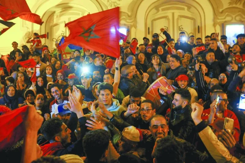 Tunisians wave Moroccan flags as they celebrate Morocco's victory in the quarter-finals of the Qatar 2022 World Cup match against Portugal, on Habib Bourguiba Avenue in Tunis on Saturday. (AFP)