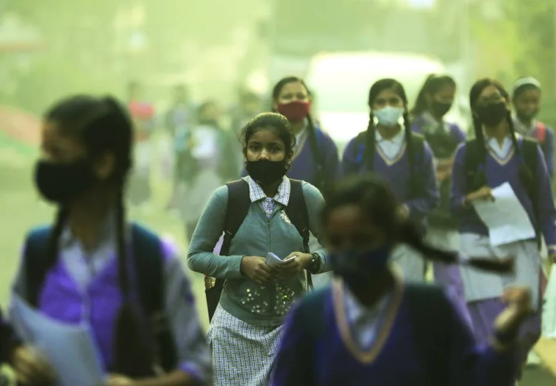 FILE PHOTO: Schoolgirls walk towards a school as they reopened after remaining closed for nearly 15 days due to a spike in air pollution, on a smoggy morning in New Delhi, India, Nov 29, 2021.