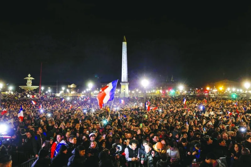 Fans wait at the Place de la Concorde for the arrival of the French national football team at the Hotel de Crillon, a day after the Qatar 2022 World Cup final match against Argentina, in central Paris on Monday night. (AFP)