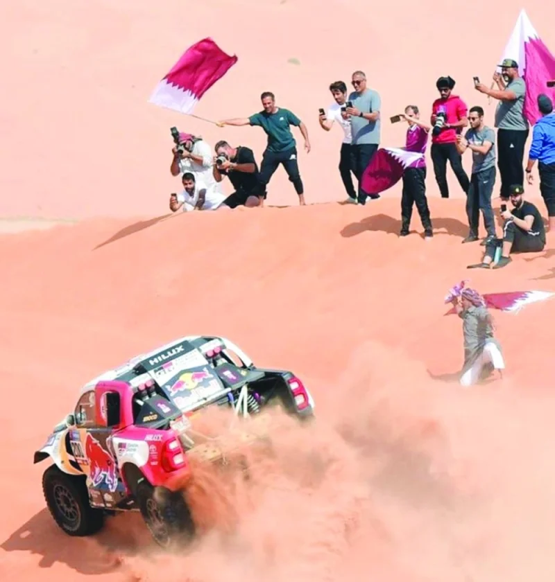 Toyota’s Qatari driver Nasser al-Attiyah and his French co-driver Mathieu Baumel drive past fans during the stage 13 of the Dakar Rally between Saybah and Al Hofuf in Saudi Arabia yesterday. 
