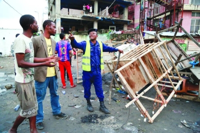 A member of the Kinshasa sanitary police brigade reacts as he dismantles informal market stalls as part of an effort to clean up the Congolese capital ahead of Pope Francis’ visit, scheduled for late January in Democratic Republic of Congo.