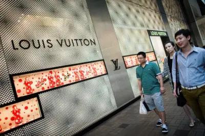 TO GO WITH AFP STORY CHINA-POLITICS-RETAIL-LUXURY,FOCUS by Stephen Coates 
In this picture taken on September 26, 2012, Chinese mainland tourists walk past a luxury shop in Hong Kong. Chinese consumers, who spent an estimated 49 billion USD on luxury goods in 2011, are poised to overtake Americans this year as the biggest buyers of luxury goods in the world.   AFP PHOTO / Philippe Lopez (Photo by PHILIPPE LOPEZ / AFP)