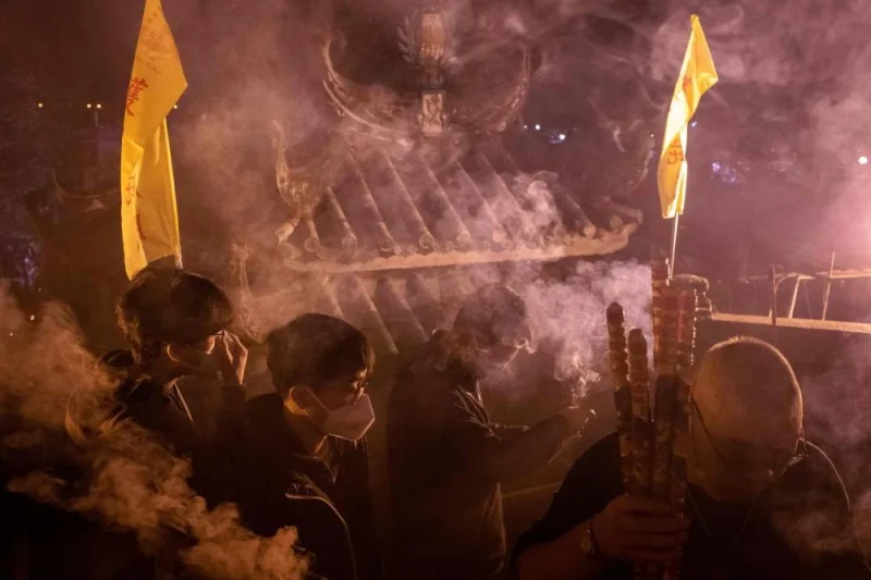 People hold incense sticks while walking around the A-Ma Temple during the start of celebrations of the Chinese Lunar New Year in Macau on January 21, 2023. (AFP)