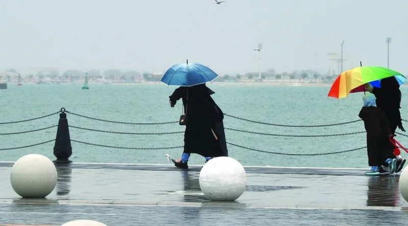 People enjoy the rainy weather with a walk through the Old Doha Port area Friday. PICTURE: Shaji Kayamkulam