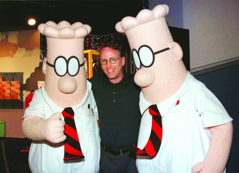 Scott Adams, the creator of Dilbert, the cartoon character that lampoons the absurdities of corporate life, poses with two Dilbert characters at a party on January 8, 1999 in Pasadena, California. (Reuters)