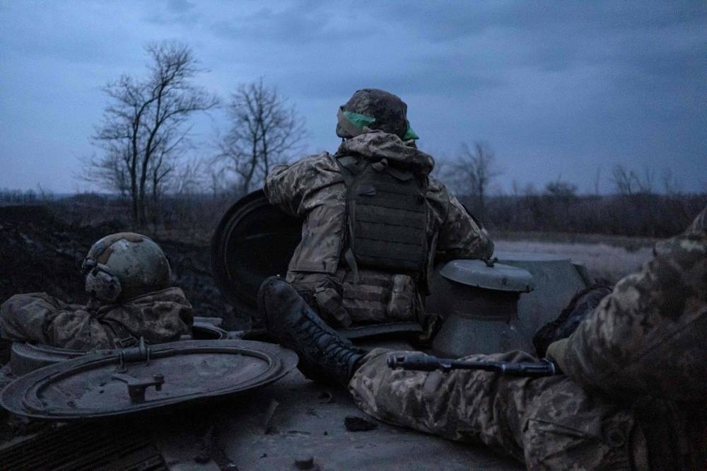 Soldiers of the Ukrainian Volunteer Army stand on a MT-LB vehicle as they drive from the front line near Bakhmut, Donetsk region, on March 11, 2023, amid the Russian invasion of Ukraine. AFP
