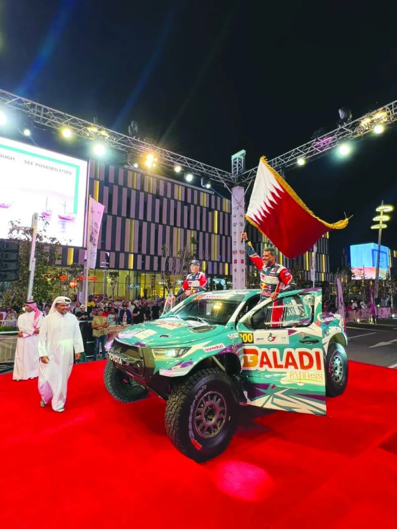 Nasser Saleh al-Attiyah waves the Qatar flag as Qatar Motor and Motorcycle Federation (QMMF) President Abdulrahman al-Mannai looks on during the ceremonial start of the Qatar International Baja at the Lusail Boulevard on Thursday.
