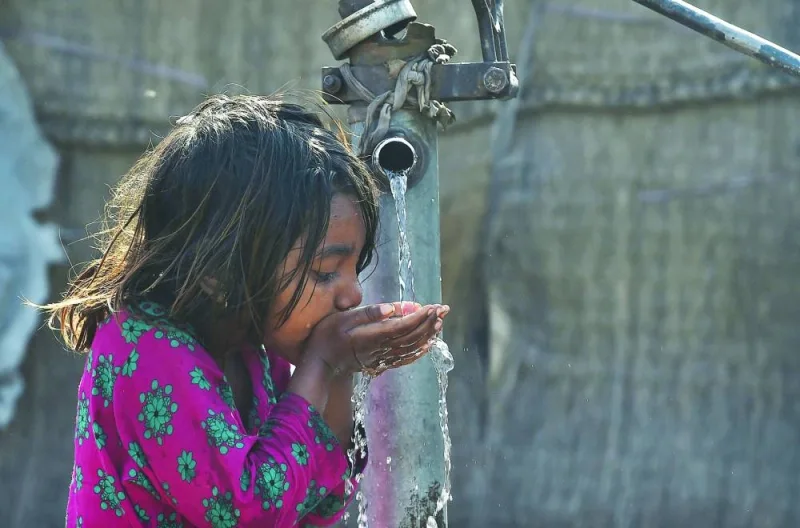 A Pakistani girl drinks water from a hand water pump in Lahore on World Water Day today. (AFP)