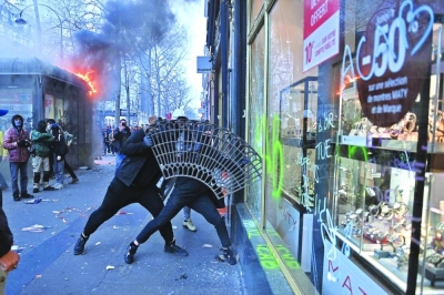Protesters use a sidewalk tree grid to break the window of a shop on the sidelines of a demonstration as part of a national day of strikes and protests in Paris.
