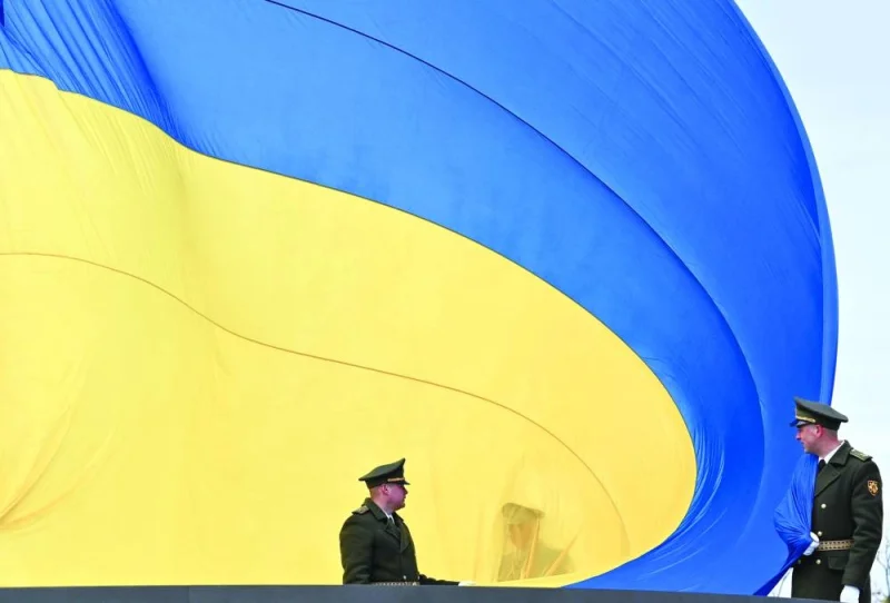 Ukrainian servicemen hold the huge national flag before it is raised on a flagpole during a ceremony marking the first anniversary of the retreat of Russian troops from the Ukrainian town of Bucha, near Kyiv.