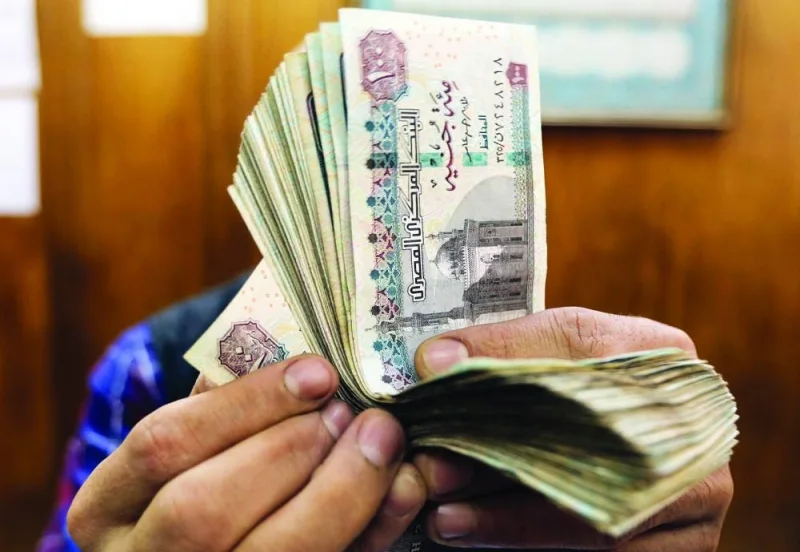 An employee counts Egyptian pounds at a foreign exchange office in central Cairo (file). S&P anticipated that the local currency would decline by about 53% by the end of this fiscal year to June 30, from 12 months earlier, “followed by a modest depreciation in the subsequent years.” The pound is down 39% since last June 30, according to data compiled by Bloomberg.