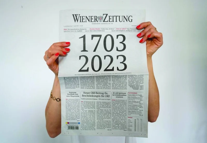 A woman holds the current issue of the Wiener Zeitung newspaper, with its front page illustrating the newspaper’s age of 320 years, in Vienna.