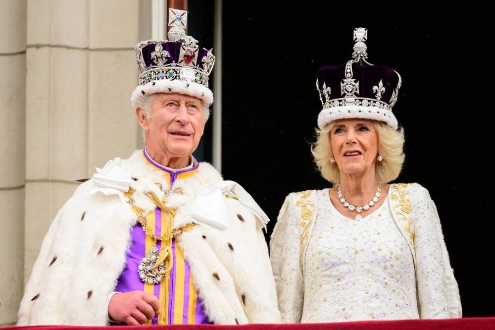 King Charles II and Queen Camilla wave from the balcony of Buckingham Palace during the Coronation. REUTERS