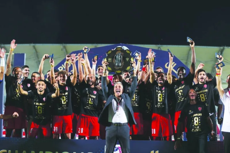 Al Duhail’s coach Hernan Crespo (centre) lifts the Falcon Shield and celebrates with his players after winning the QNB Stars League yesterday. 