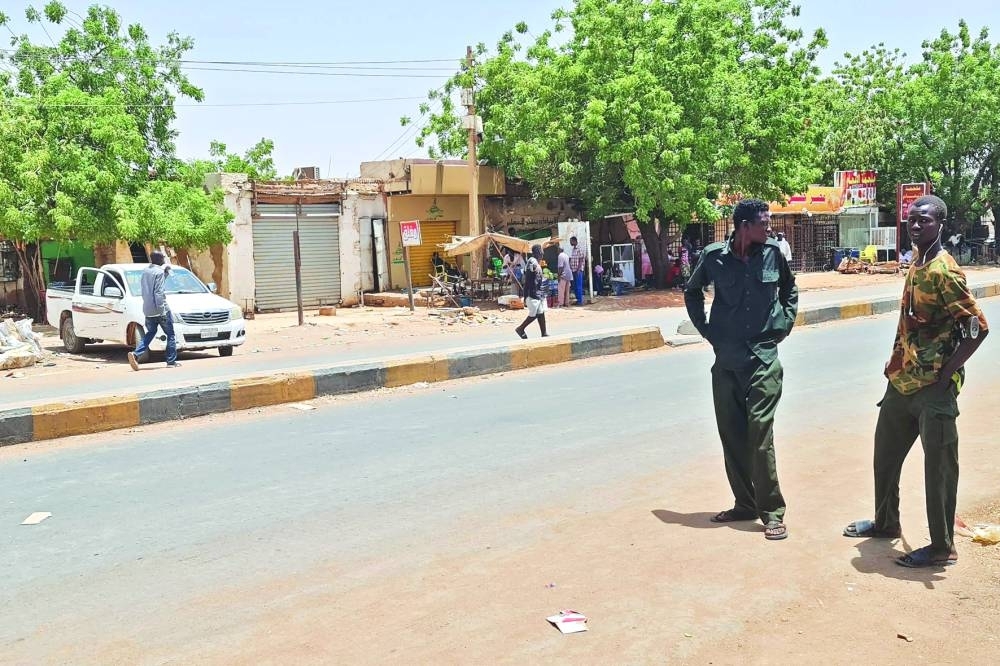 Smoke rises above buildings in Khartoum, yesterday. Below: Security forces loyal to the Sudanese army chief stand along a street in war-torn Khartoum, on Friday.