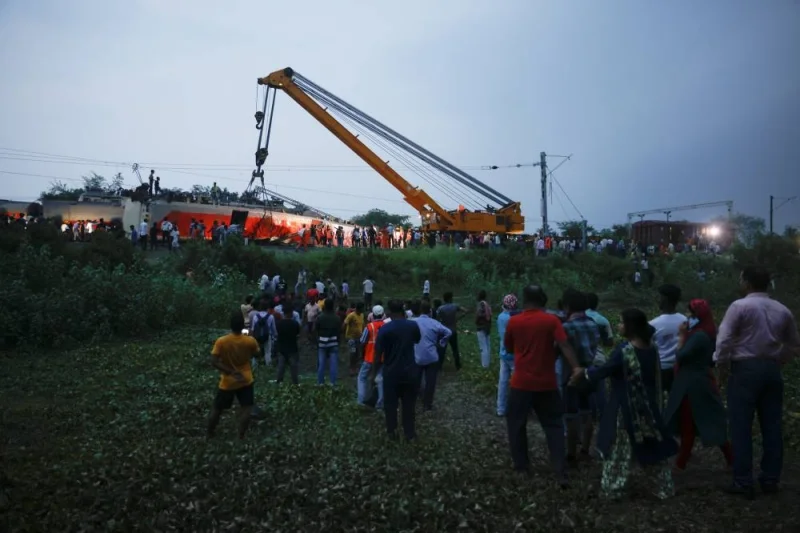 People watch as a crane operates at the site of a train collision after the accident in Balasore district in the eastern state of Odisha. REUTERS/Adnan Abidi