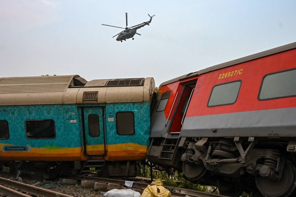 An army helicopter flies above the carriage wreckage of a three-train collision near Balasore, in India&#039;s eastern state of Odisha. DIBYANGSHU SARKAR / AFP
