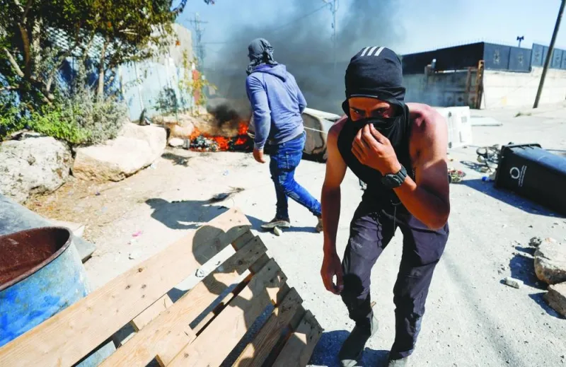 A Palestinian covers his face during clashes with troops after settlers attack Umm Safa village near Ramallah, in the occupied West Bank, on Saturday.