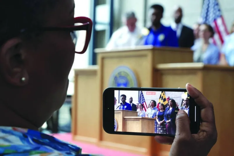 A woman takes a video as Baltimore Mayor Brandon Scott speaks during a news conference at the police headquarters on Monday.