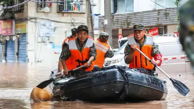 (FILES) This file photo taken on July 4, 2023 shows paramilitary policemen searching an area after it was flooded by heavy rains in China's southwestern Chongqing. - Fifteen people have been killed and four are missing after torrential rain in southwest China, state media said on July 5, 2023. (Photo by STR / AFP) / China OUT / NO USE AFTER AUGUST 4, 2023 05:30:13 GMT - CHINA OUT
