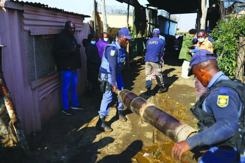 Police officers remove a gas cylinder, allegedly used in illegal mining, in the Angelo shack settlement, near Boksburg, east of Johannesburg, South Africa on Thursday.