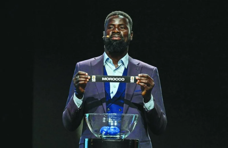 Former Ivorian football player Emmanuel Eboue shows the ticket of Morocco during the qualifying draw for the Africa zone of the 2026 FIFA World Cup in Abidjan on Thursday. (AFP)