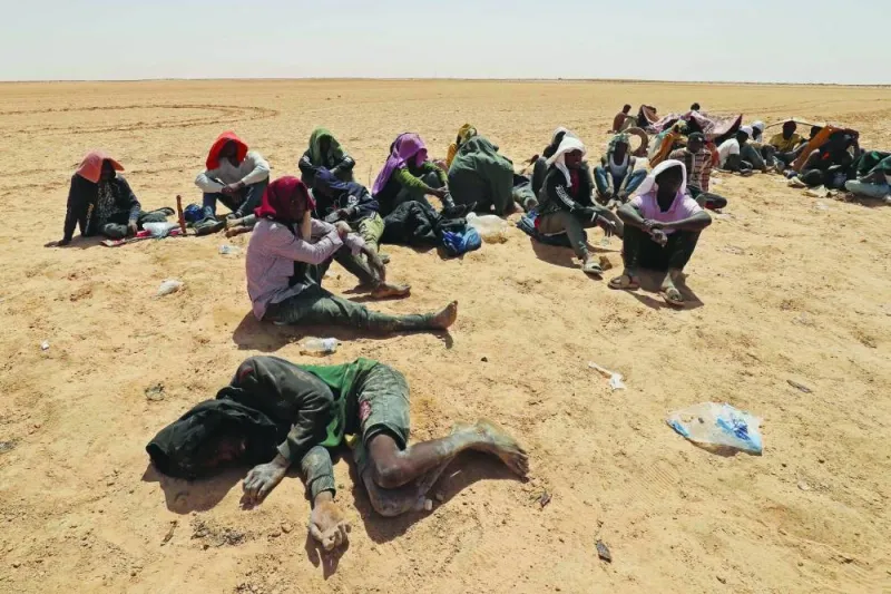 
Migrants from sub-Saharan African countries, who claim to have been abandoned in the desert by Tunisian authorities without water or shelter, sit in an uninhabited area near Libya’s border town of Al-Assah. 