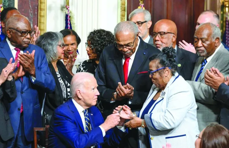
US President Joe Biden hands a pen to Till family member Dr Marvel Parker, Executive Director of the Emmett Till & Mamie Till-Mobley Institute, after signing a proclamation establishing the Emmett Till and Mamie Till-Mobley National Monument in Illinois and Mississippi yesterday. (AFP) 