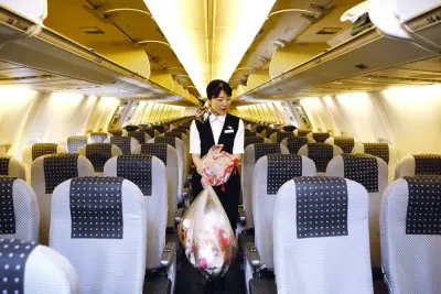 A cabin attendant carries bags of trash as she conducts her cleaning duties in the cabin of a Japan Airlines Co airplane at Haneda Airport in Tokyo (file). Handling cabin waste in airlines poses several challenges due to various factors such as limited storage capacity, weight and balance considerations and hazardous materials.