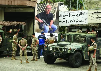 
Lebanese army members stand near a poster of Fadi Bejjani who died during exchange of fire at the area where a truck was overturned the previous night, in the town of Kahaleh, Lebanon. 
