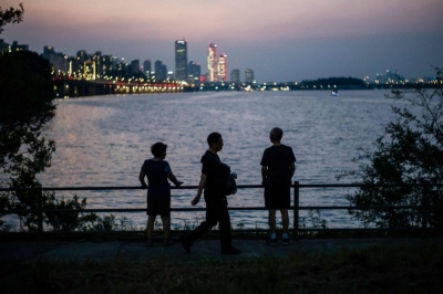 People stop to admire the evening view of the Han River in Seoul on August 17, 2023. (Photo by ANTHONY WALLACE / AFP)