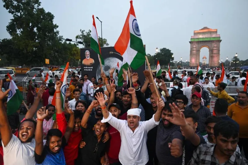 People wave Indian national flags as they celebrate the successful lunar landing of Chandrayaan-3 spacecraft on the south pole of the Moon, in New Delhi. AFP