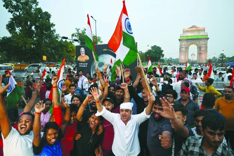 People wave Indian national flags as they celebrate the successful lunar landing of Chandrayaan-3 spacecraft on the south pole of the Moon, in New Delhi yesterday.