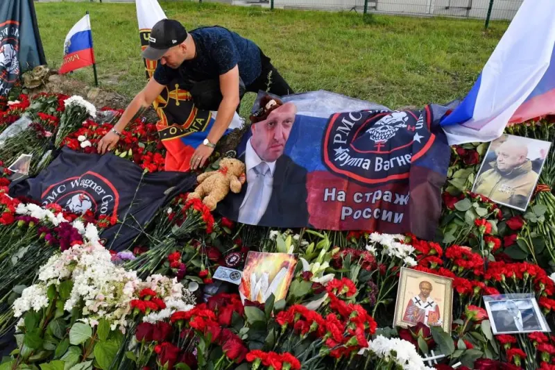 A man arranges a flag bearing the logo of private mercenary group Wagner at a makeshift memorial for Yevgeny Prigozhin in front of the Private Military Company (PMC) Wagner Centre in Saint Petersburg, on August 25. AFP