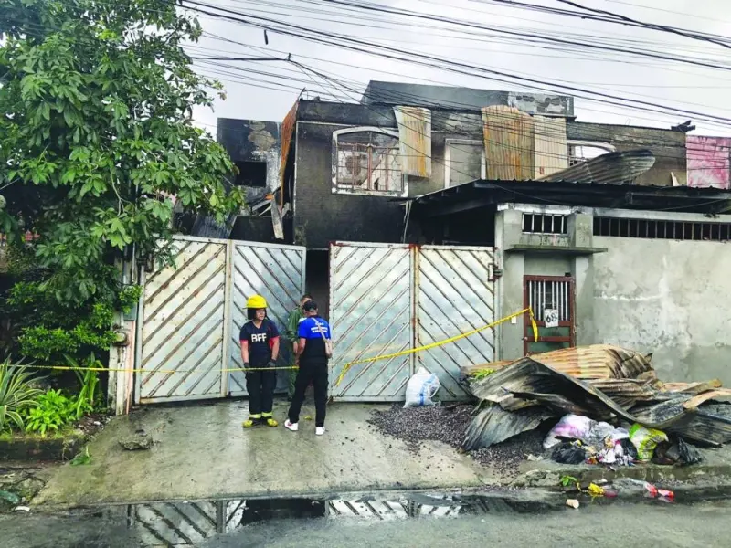 
Rescuers and village officials stand in front of a burnt residential building after it was engulfed in a fire in Quezon City, Metro Manila, Philippines, yesterday. 