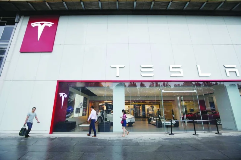 
People walk past a showroom outside Tesla China headquarters in Beijing. Tesla yesterday unveiled a restyled Model 3 with a longer driving range in China and other export markets for its Shanghai factory including Europe, putting pressure on rivals. 