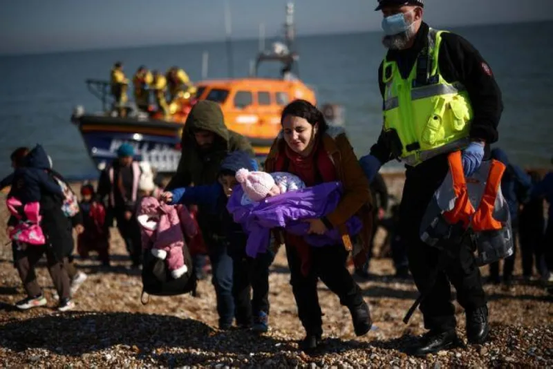 Migrants walk up the shore after being rescued by the RNLI (Royal National Lifeboat Institution) while crossing the English Channel, in Dungeness, Britain, March 15, 2022. REUTERS/Henry Nicholls