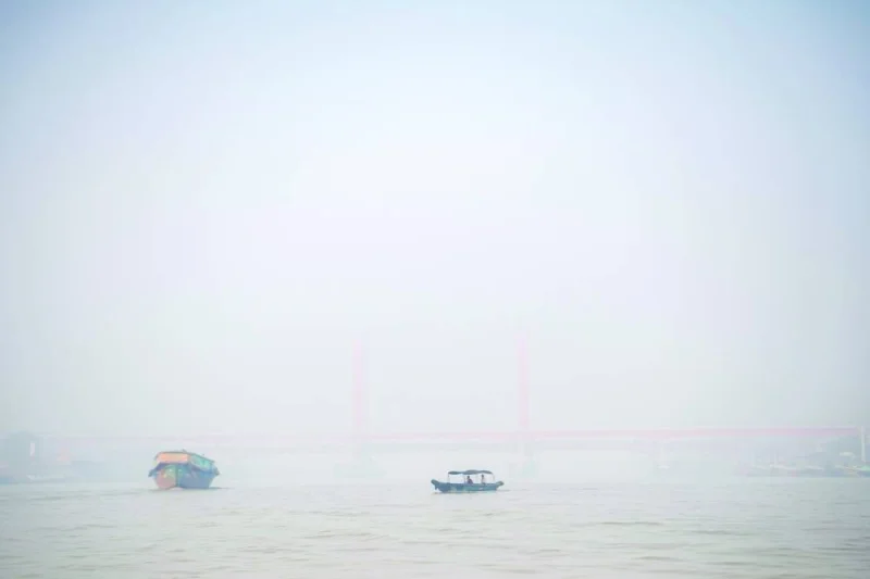 Passengers sit on a wooden boat crossing the Musi river that is covered by smog due to wildfires, in Palembang, South Sumatra province, Indonesia.