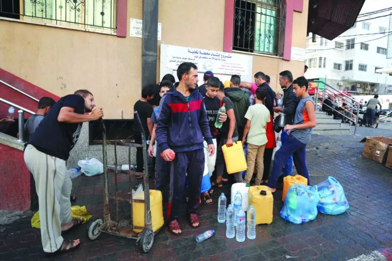 
Palestinians line up to fill water canisters in Gaza City, yesterday. 