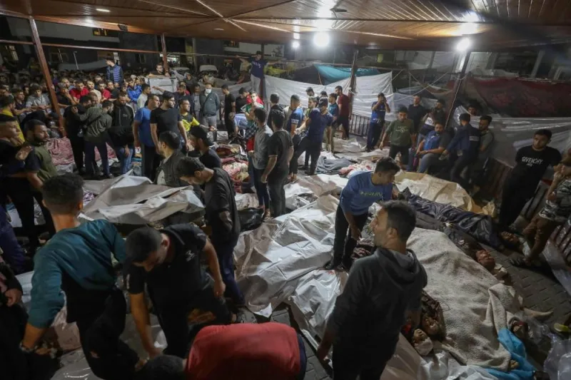 People gather around bodies of Palestinians killed in Israeli airstrikes on the Ahli Arab hospital in central Gaza after they were transported to Al-Shifa hopsital, Tuesday. AFP