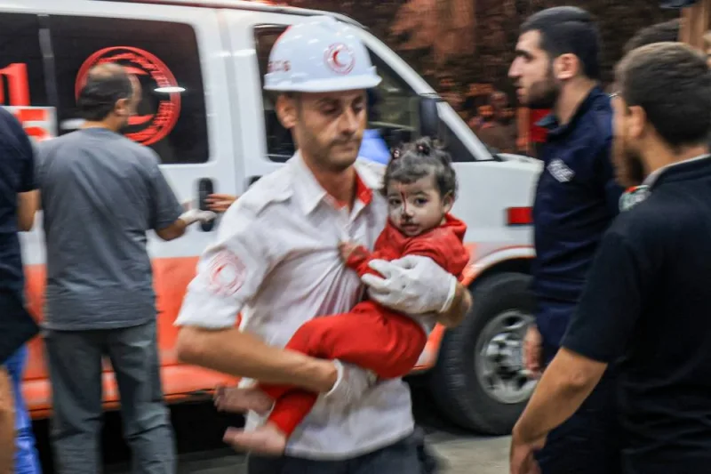 A Palestinian paramedic carries a child injured in an Israeli air strike at the Nasser hospital in Khan Yunis in the southern of Gaza Strip, Tuesday. AFP