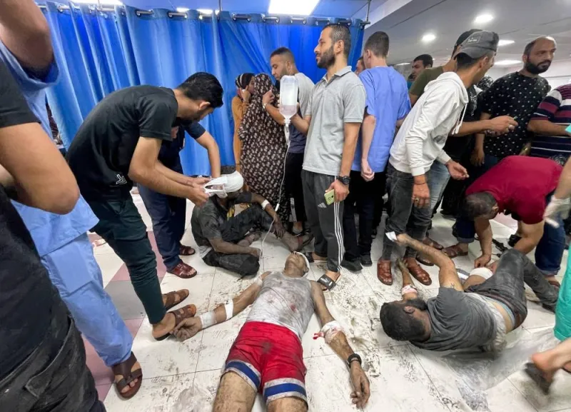 People stand next to Palestinians, who were wounded in an Israeli strike, at Shifa hospital in Gaza City, on Monday. REUTERS