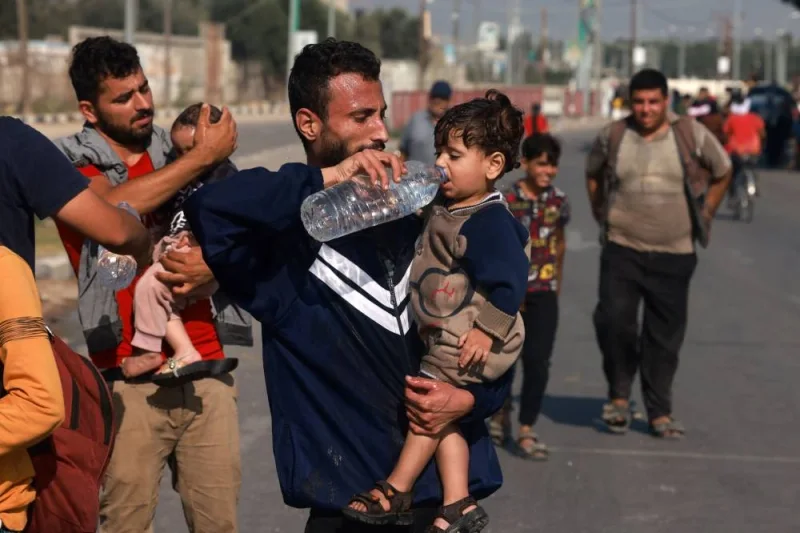 Men help toddlers to drink some water upon reaching the central Gaza Strip on foot via the Salah al-Din road on their way to the southern part of the Palestinian enclave on Sunday. AFP