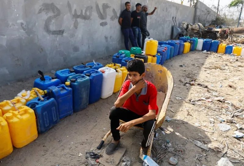 A child sits next to containers, as Palestinians collect water, amid a lack of clean and drinking water in Rafah, in the southern Gaza Strip, on Sunday. REUTERS